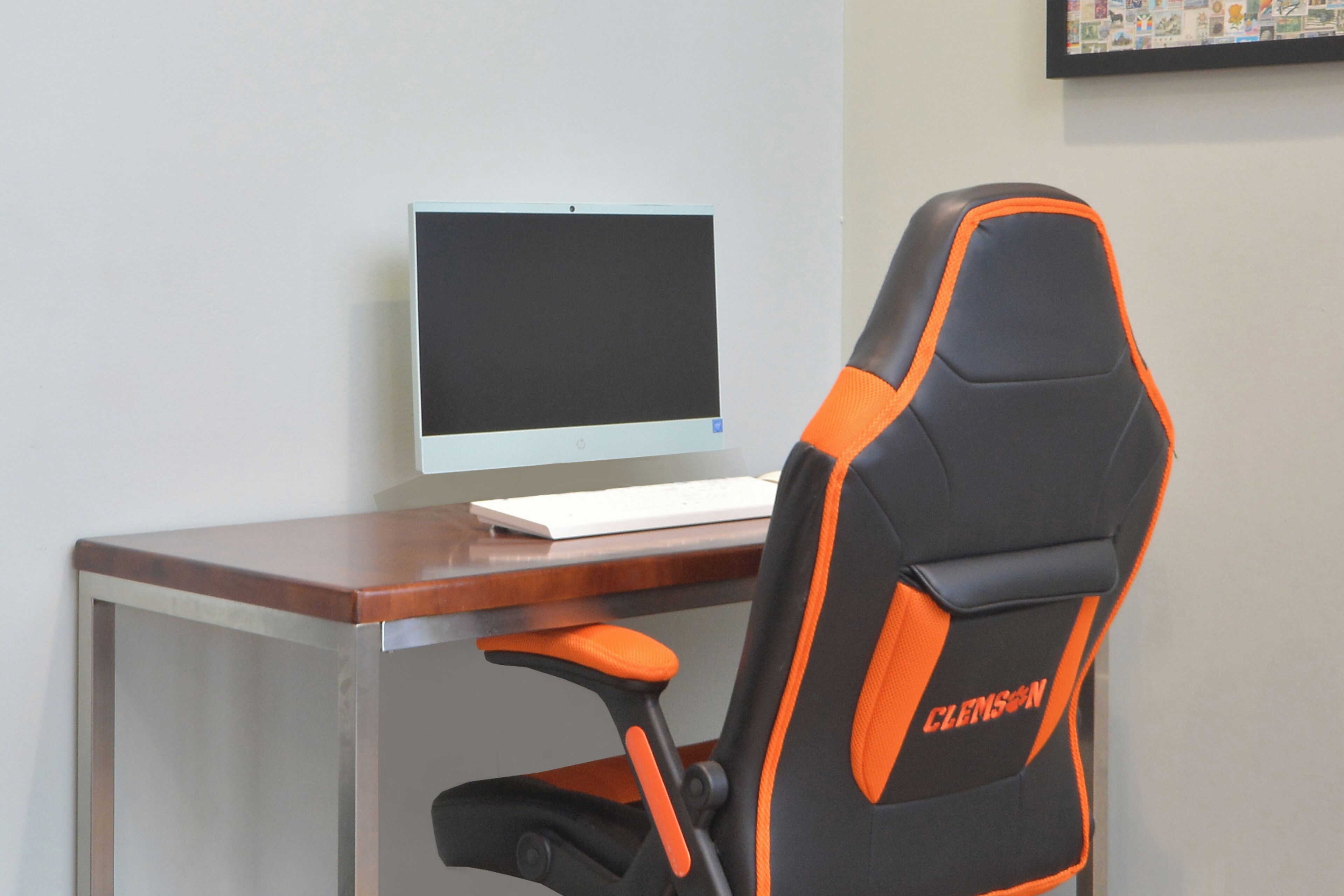 Un escritorio con una computadora portátil y una silla de oficina con la marca Clemson.