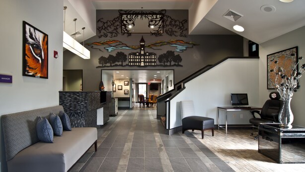 Un espace d’accueil comprenant un comptoir de réception, un canapé, un escalier et un mur décoré d’œuvres d’art.