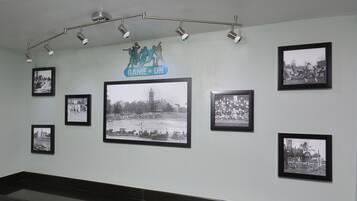 A wall with multiple black and white photographs, a 'GAME ON' sign, and a row of spotlights.