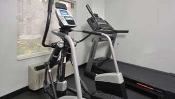 Een sportschool met cardioapparaten, waaronder een loopband en een crosstrainer, plus een bankje.