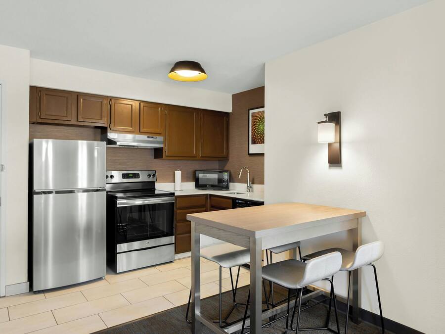 A modern kitchen with stainless steel appliances, wooden cabinets, and a dining area with a table and chairs.