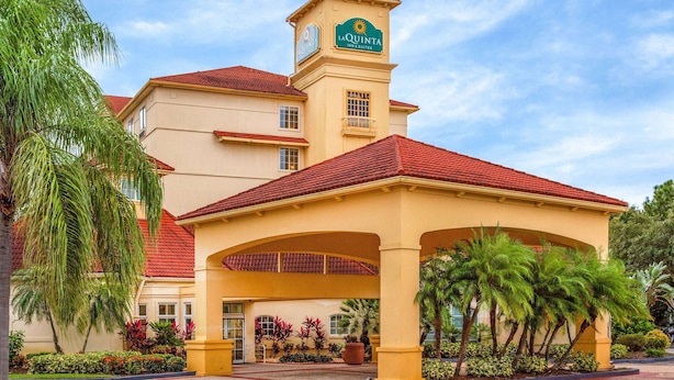 A hotel with a prominent tower, a red-tiled roof, and a landscaped entrance area with palm trees.