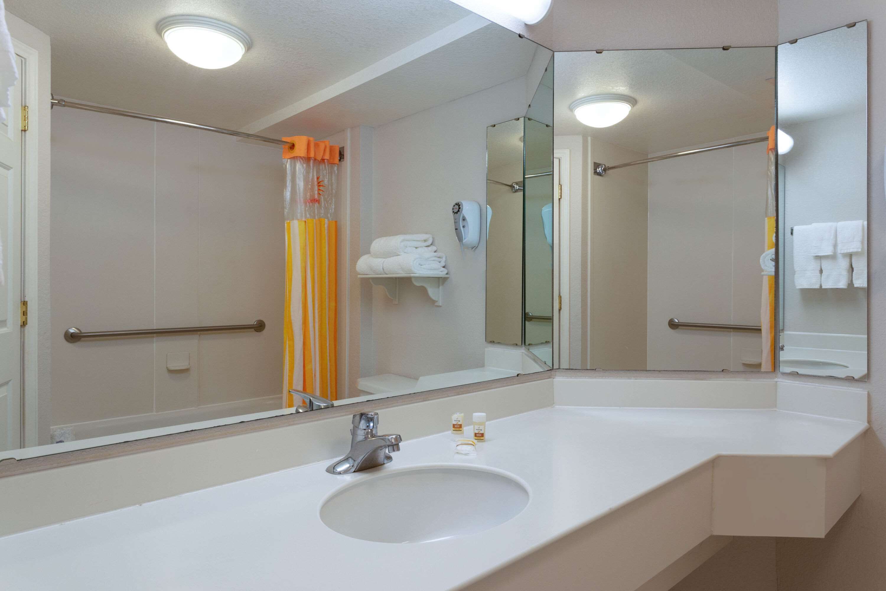 A modern bathroom with a large mirror, white sink, and a glass shower enclosure.