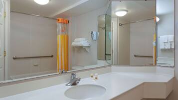 A modern bathroom with a large mirror, white sink, and a glass shower enclosure.