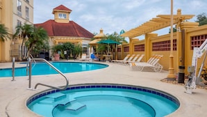 A pool area with a circular hot tub, lounge chairs, and a covered seating area.