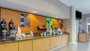 A hotel reception area with a coffee station, a fruit display, and a television mounted on the wall.
