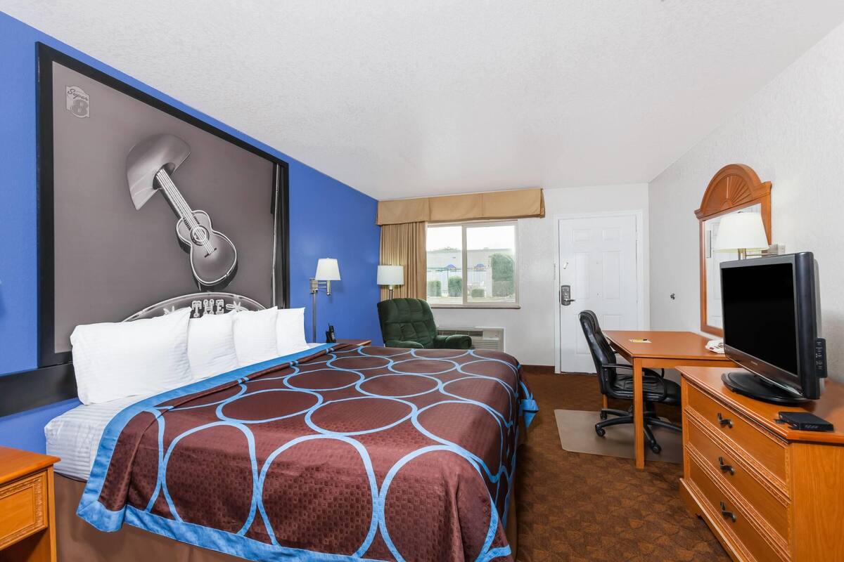 A hotel room with a bed, a desk with a television, a chair, and a window with a view.