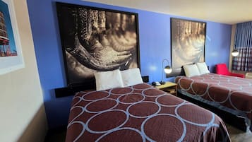 Habitación de hotel con dos camas, una mesita de noche, una lámpara y obras de arte en las paredes.