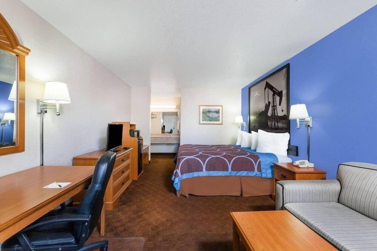 A hotel room with a bed, desk, chair, and a couch.