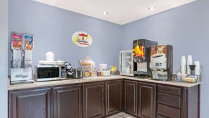 A breakfast bar with a microwave, coffee machine, and cereal dispensers. - Super 8 by Wyndham Cleburne (Cleburne)