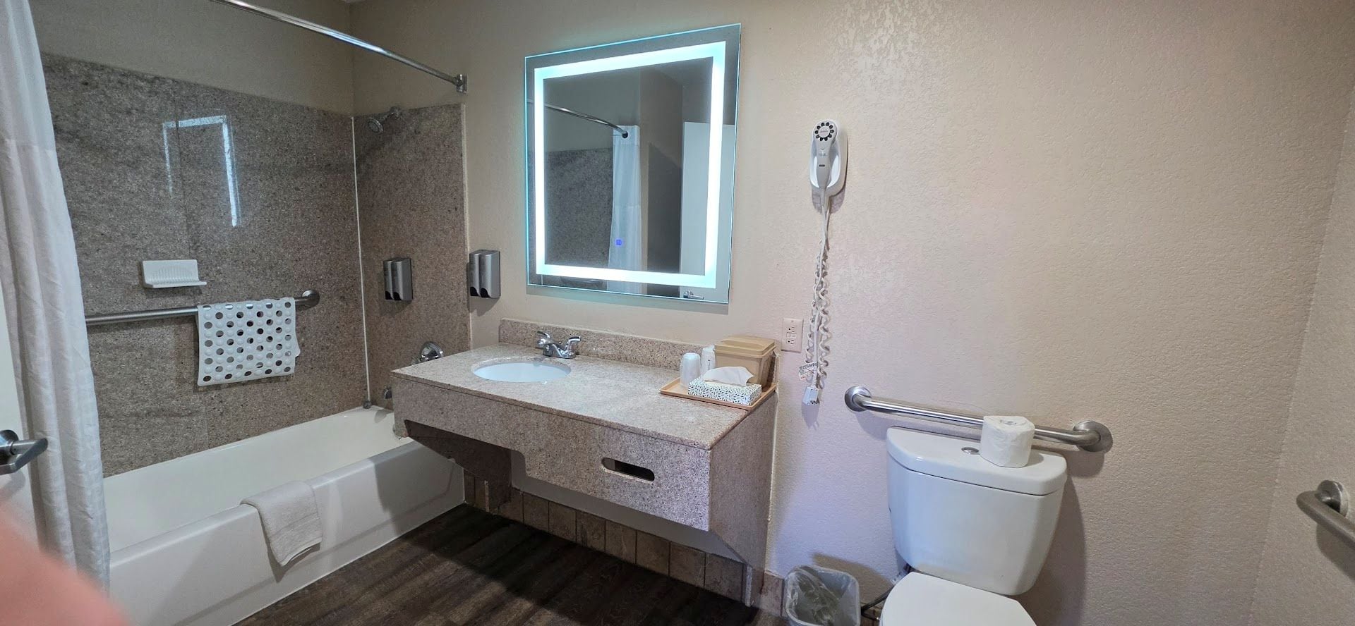 A bathroom with a bathtub, two sinks, a toilet, a towel rack, a mirror, and a hairdryer.
