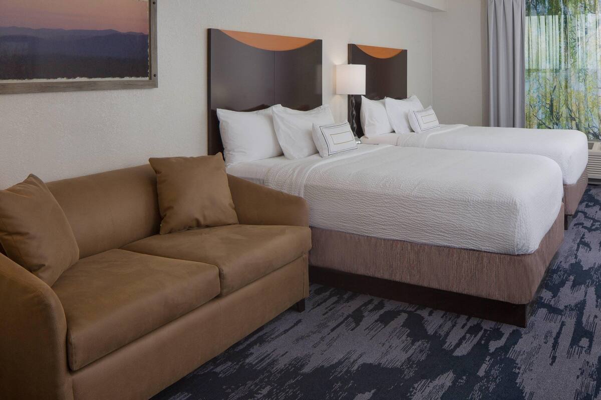 A hotel room with a large bed, a sofa, and a painting on the wall.