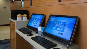 Zwei Laptops auf einem Schreibtisch mit Tastatur und Maus, eine kleine Pflanze und eine blaue Ordnermappe.