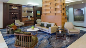 Eine moderne Lobby mit einer Couch, Sesseln, einem Couchtisch und einer Wanddekoration.