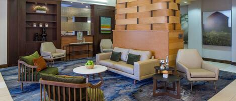 A modern lobby with a sofa, chairs, a coffee table, and a decorative wall.