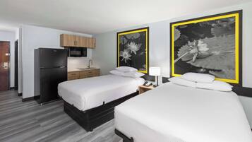 Een hotelkamer met twee bedden, een koelkast, een magnetron, een wastafel en kunst aan de muren.