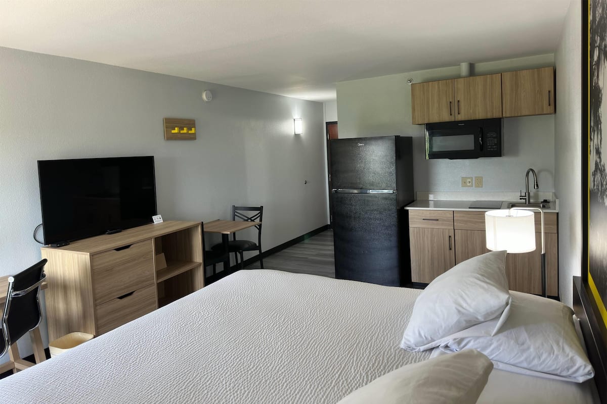 Habitación de hotel con cama, escritorio, televisor, refrigerador y microondas.