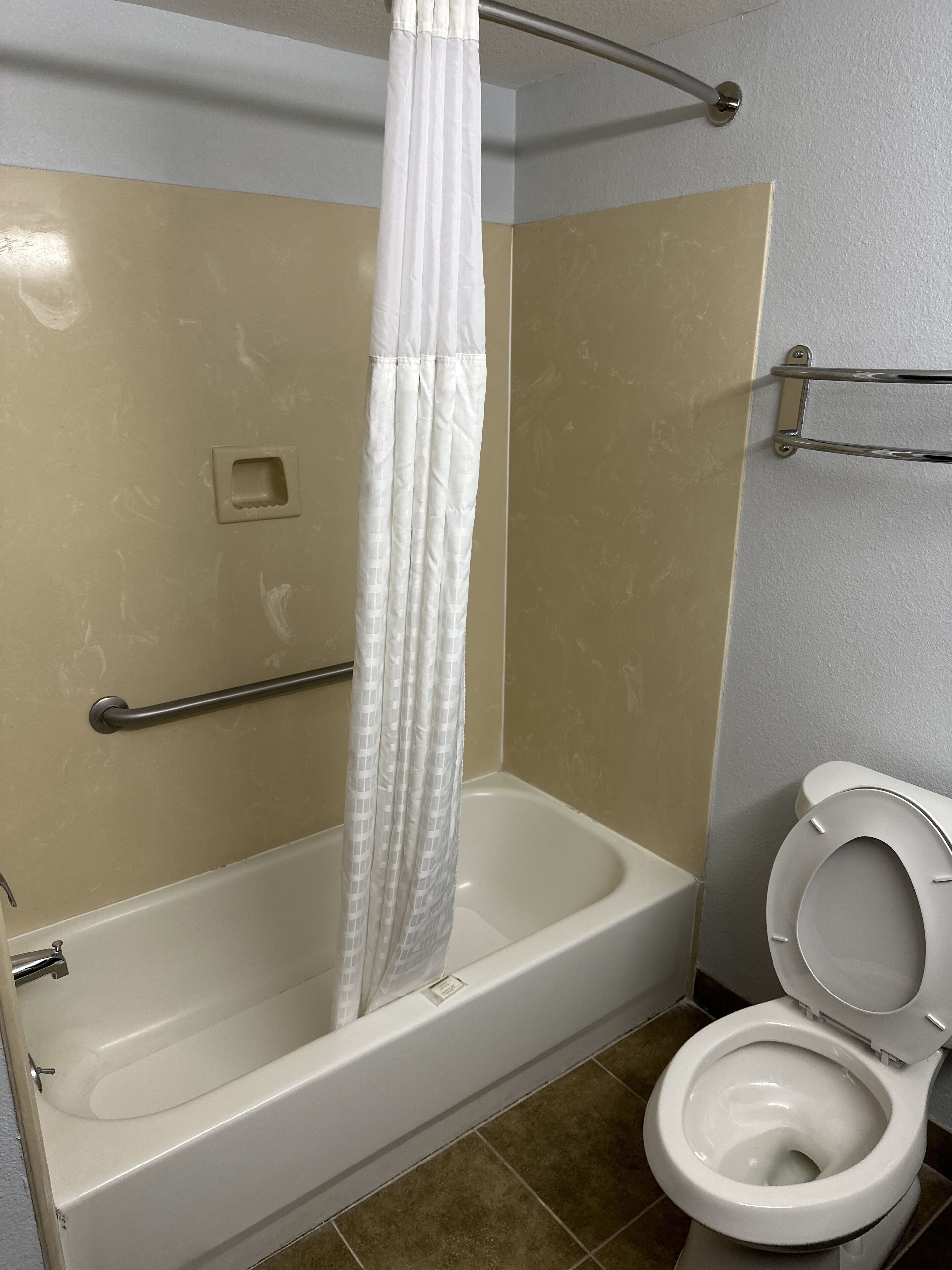 Un baño con bañera, inodoro y cortina de ducha.