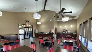 Un restaurante moderno con varias mesas y cabinas, ventiladores de techo y una cocina a la vista.
