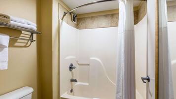Une douche avec une porte en verre, un porte-serviettes et des toilettes.