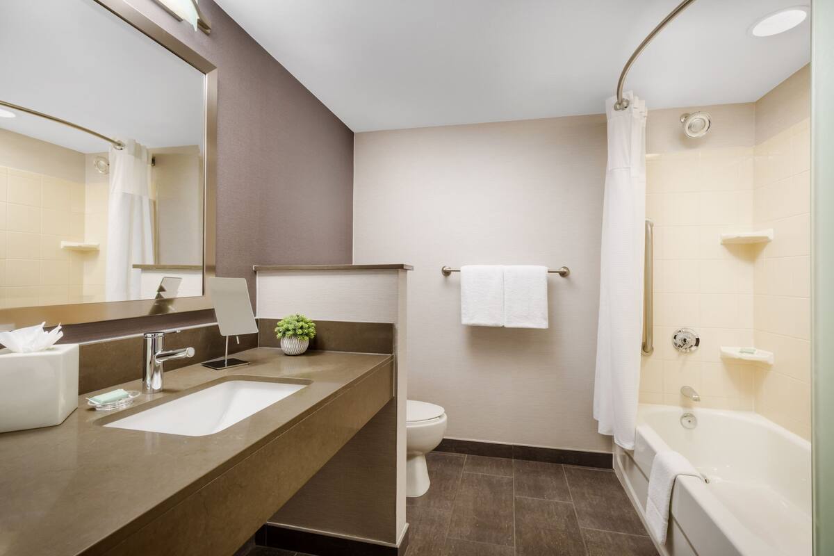 A modern bathroom with a sink, toilet, and bathtub.