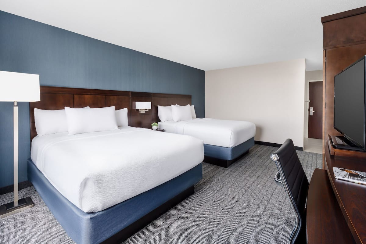 Une chambre d’hôtel avec deux lits, une télévision et un bureau.
