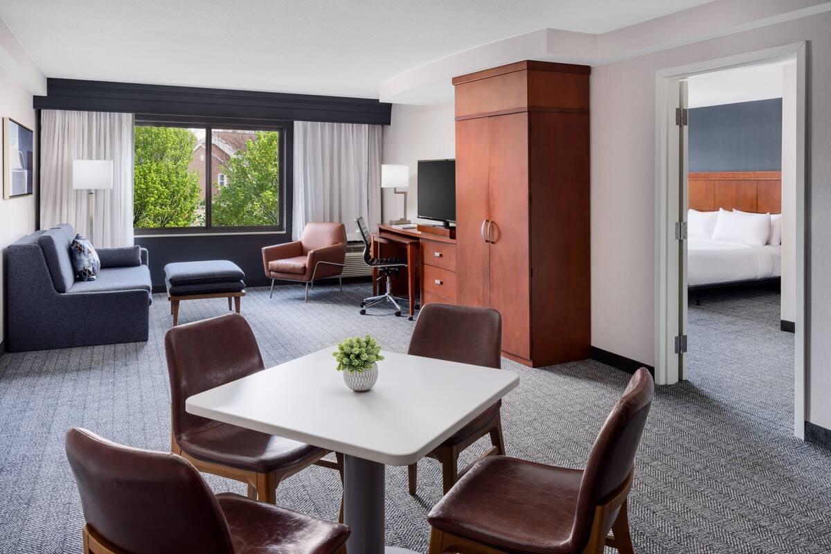 Une chambre d’hôtel comprenant un lit, un bureau, une télévision, un canapé et un coin repas avec des chaises et une table.