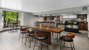 Un área de bar moderna con una barra larga, taburetes y una máquina de café.