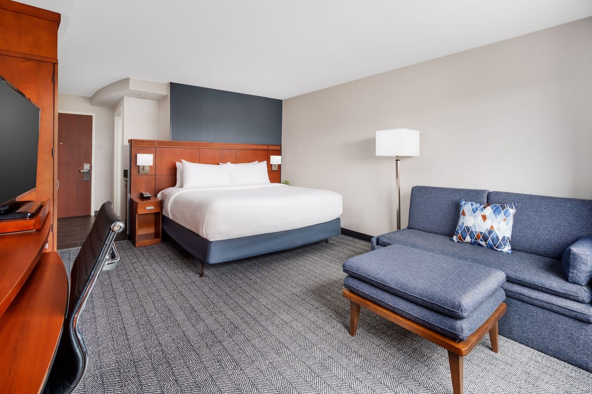 Une chambre d’hôtel avec un grand lit, un canapé, un bureau et une télévision.
