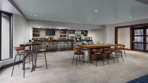 Un área de bar moderna con una barra larga, taburetes y una máquina de café.
