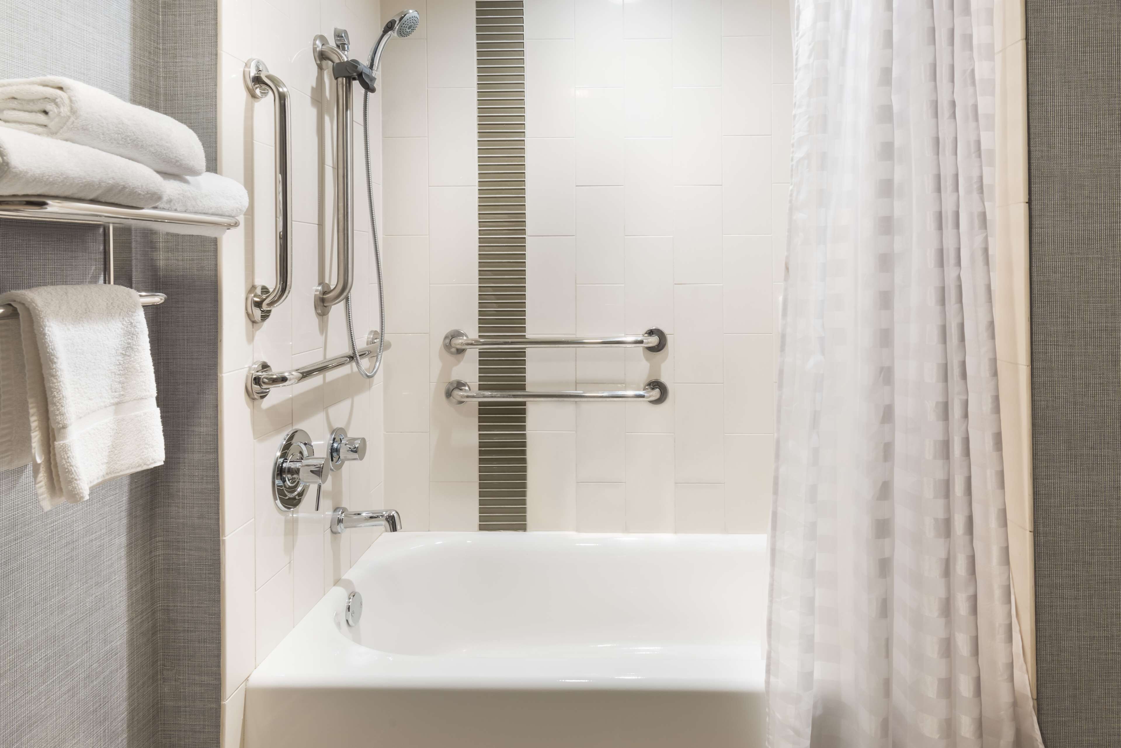 Un baño moderno con bañera, barras de apoyo y ducha.