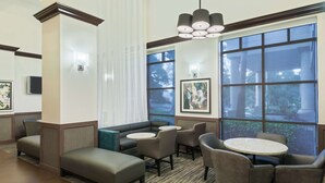 A hotel lobby with seating areas, a large window with a view, and a chandelier.