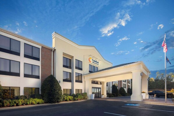 A Comfort Inn & Suites hotel with a covered entrance, a parking lot, and an American flag.