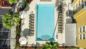Vista aérea de una piscina con sillones de descanso y una pequeña cascada.
