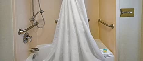A bathroom with a bathtub, a shower with a handheld showerhead, and a towel rack.