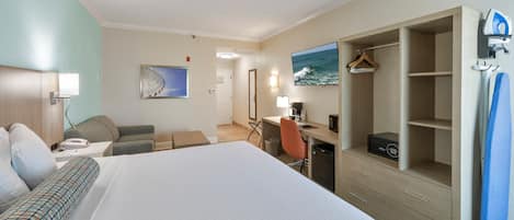 Une chambre d’hôtel avec un grand lit, un bureau avec un ordinateur, une chaise, un porte-manteau et un téléviseur.