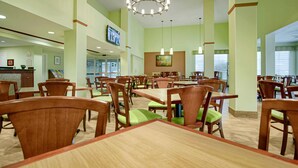 Un comedor con mesas y sillas de madera, un mostrador de recepción y una pantalla de televisión.