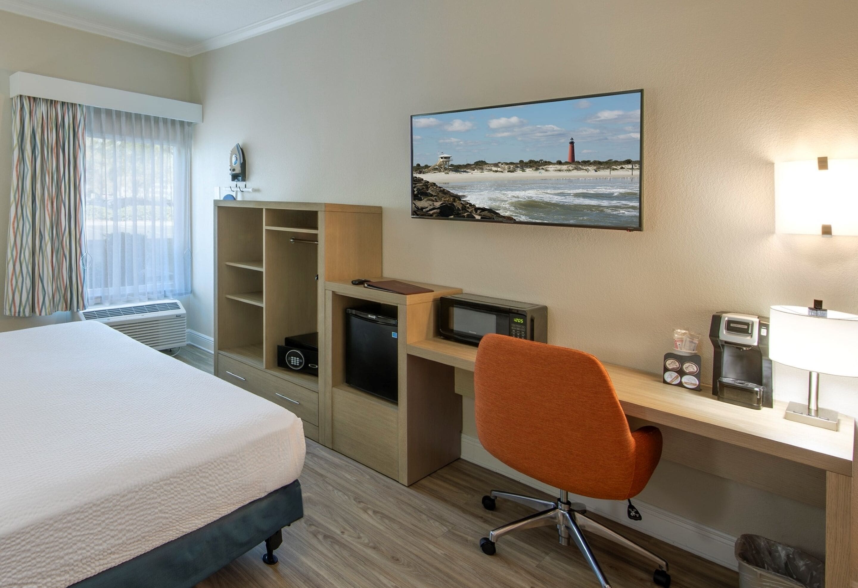 Een hotelkamer met een bed, een bureau met een computer, een magnetron en een koffiezetapparaat.
