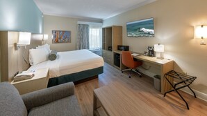 A hotel room with a bed, desk, chair, and a TV on the wall.