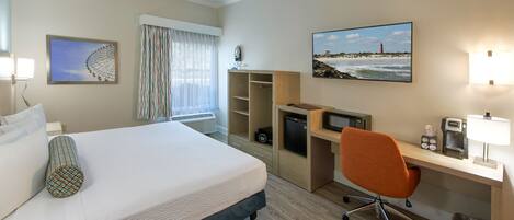 Een hotelkamer met een bed, bureau, stoel en een schilderij van een vuurtoren.