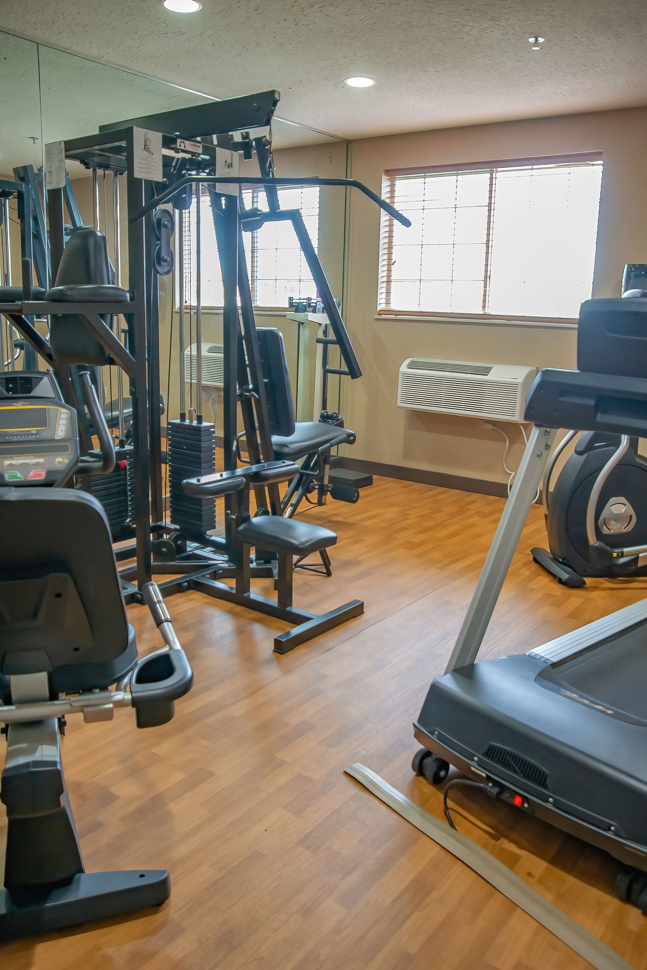 A gym with various exercise equipment including a treadmill, weight machines, and a bench.
