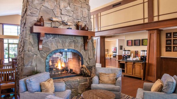 A cozy lobby with a stone fireplace, comfortable seating, and a bar area. - Hampton Inn & Suites Rochester/Victor (Victor)