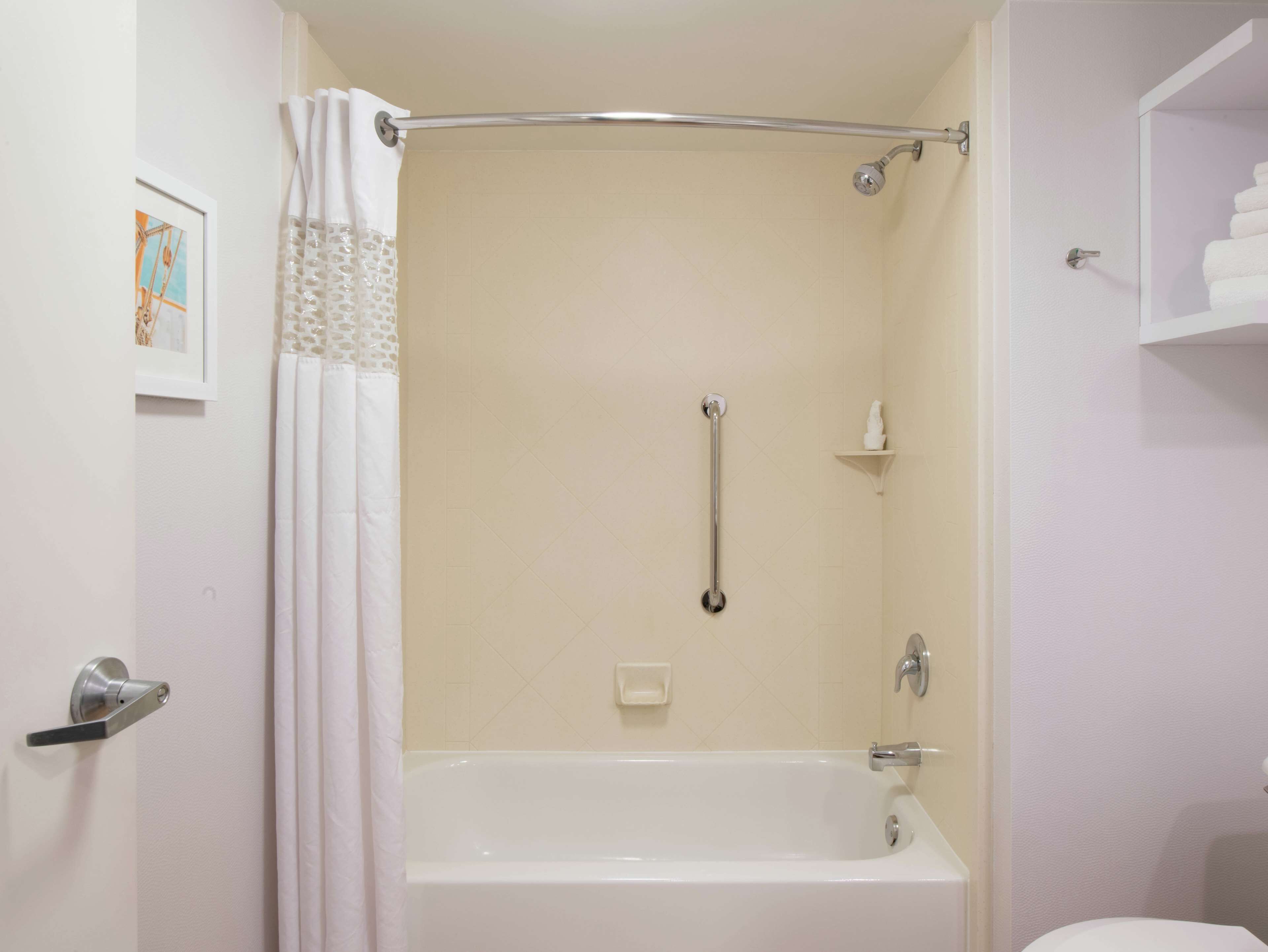 Un baño con bañera, ducha, barra de apoyo y retrete.