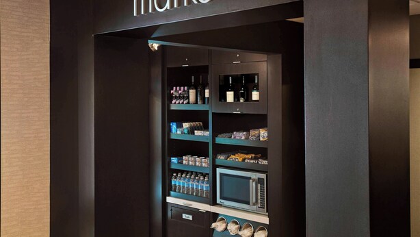 Een automatenruimte met een bord waarop 'the market' staat, en diverse artikelen, waaronder drankjes en snacks.