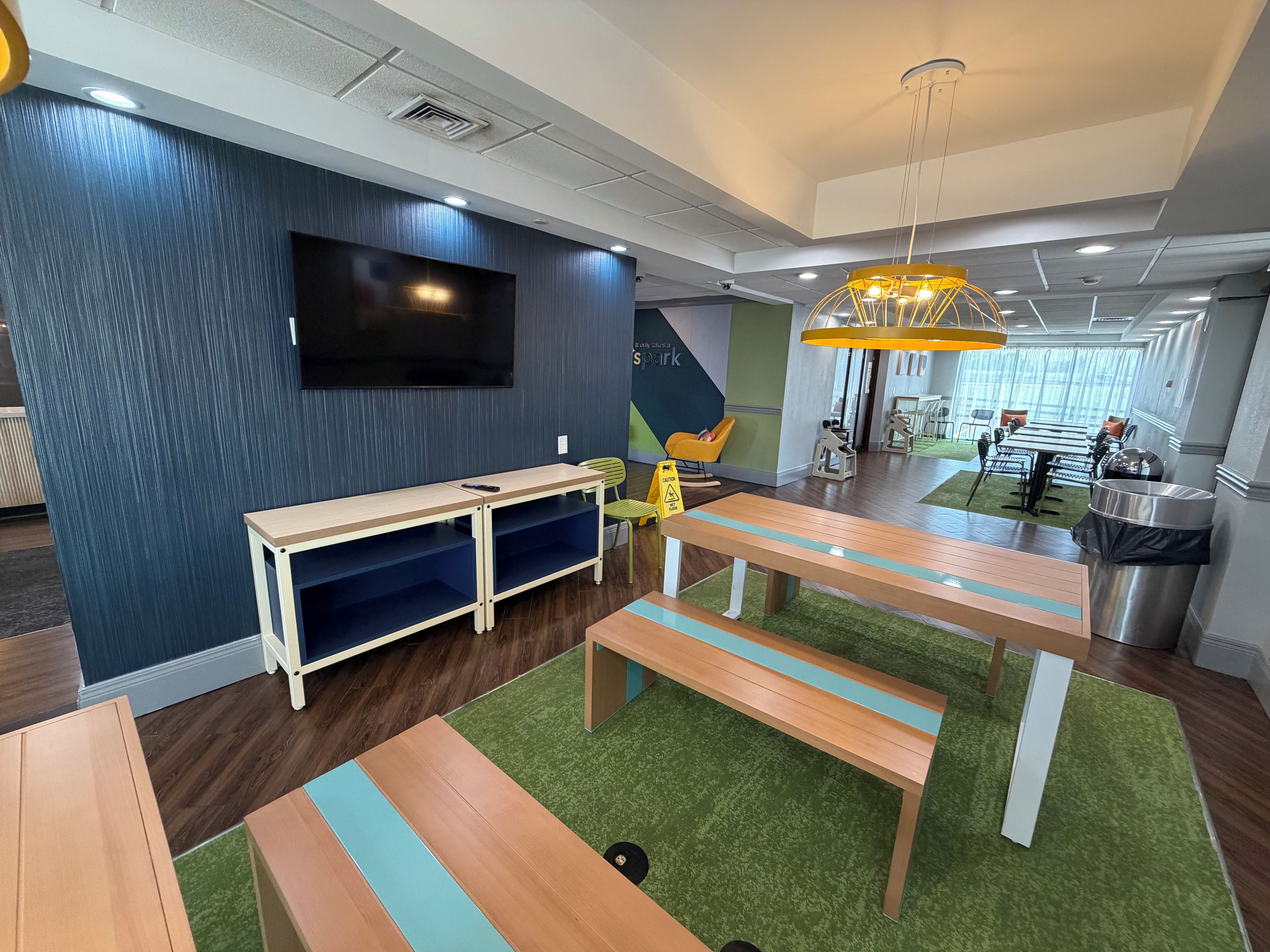 A modern interior with a dining area, a flat-screen TV mounted on the wall, and a unique yellow chandelier.