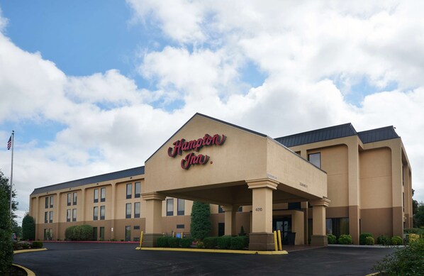 A Hampton Inn hotel with a beige facade, large windows, and a flat roof.