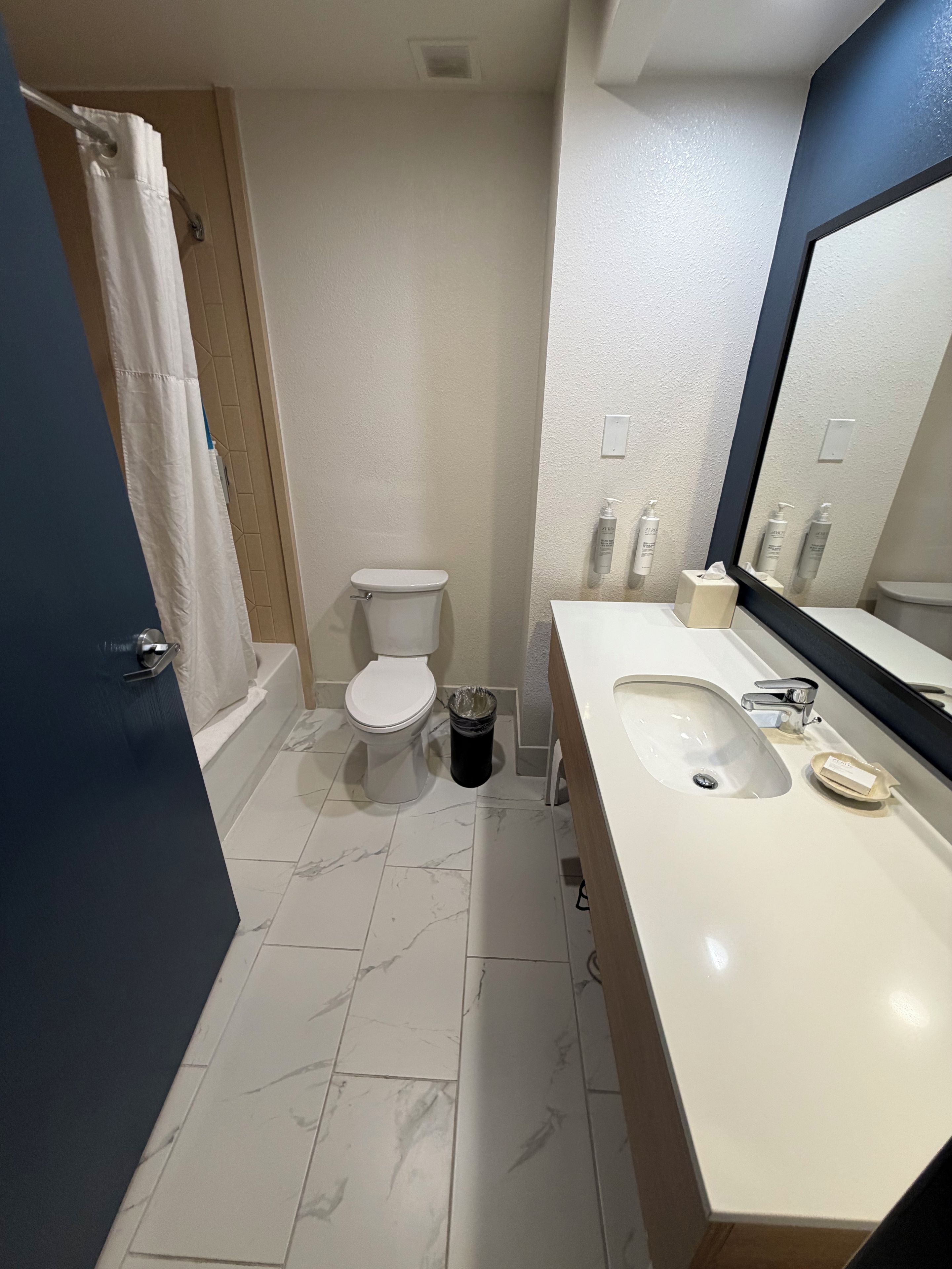 Een badkamer met toilet, wastafel en spiegel.