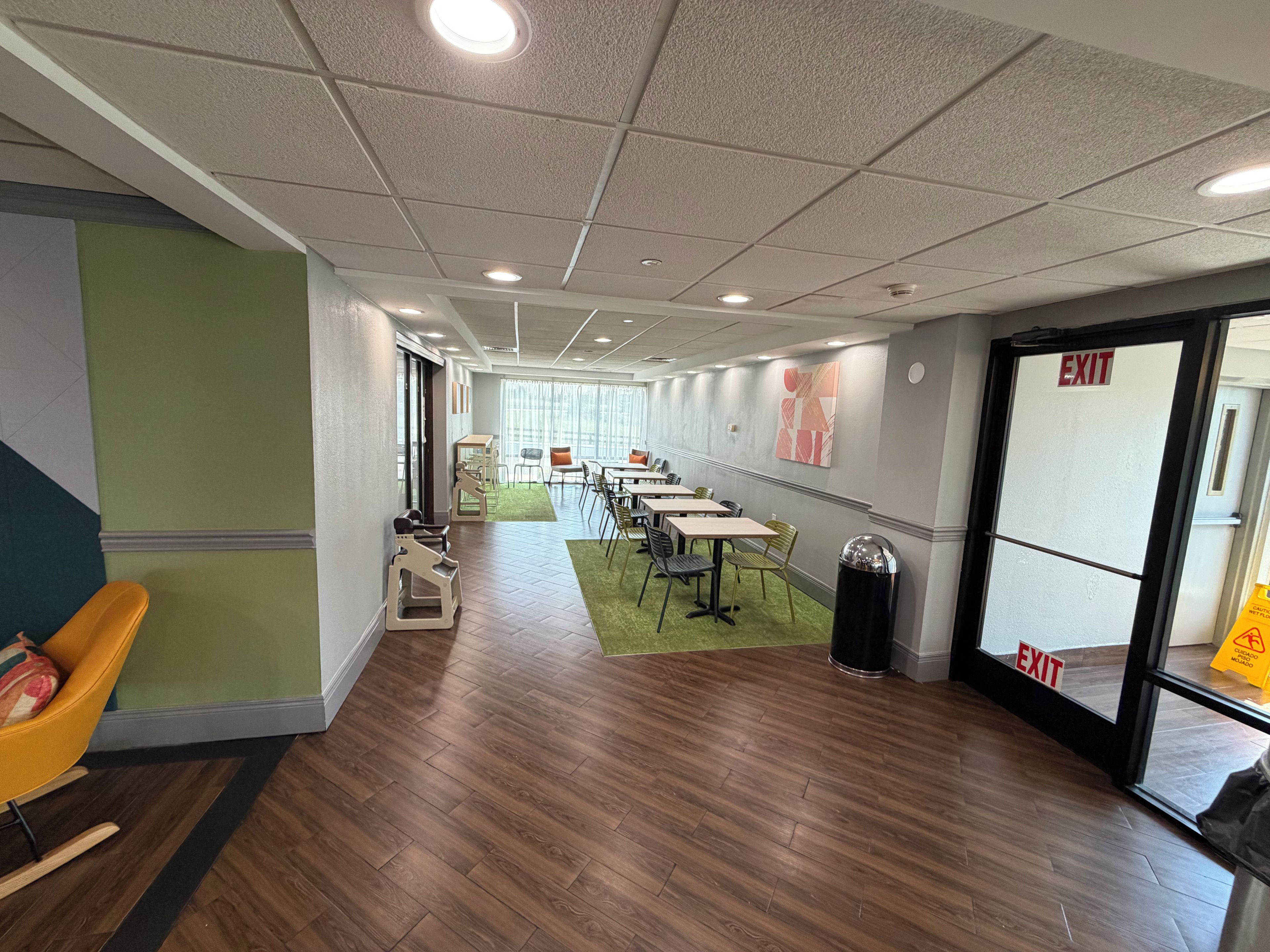 A hotel lobby with a long corridor, seating area, and an exit door.