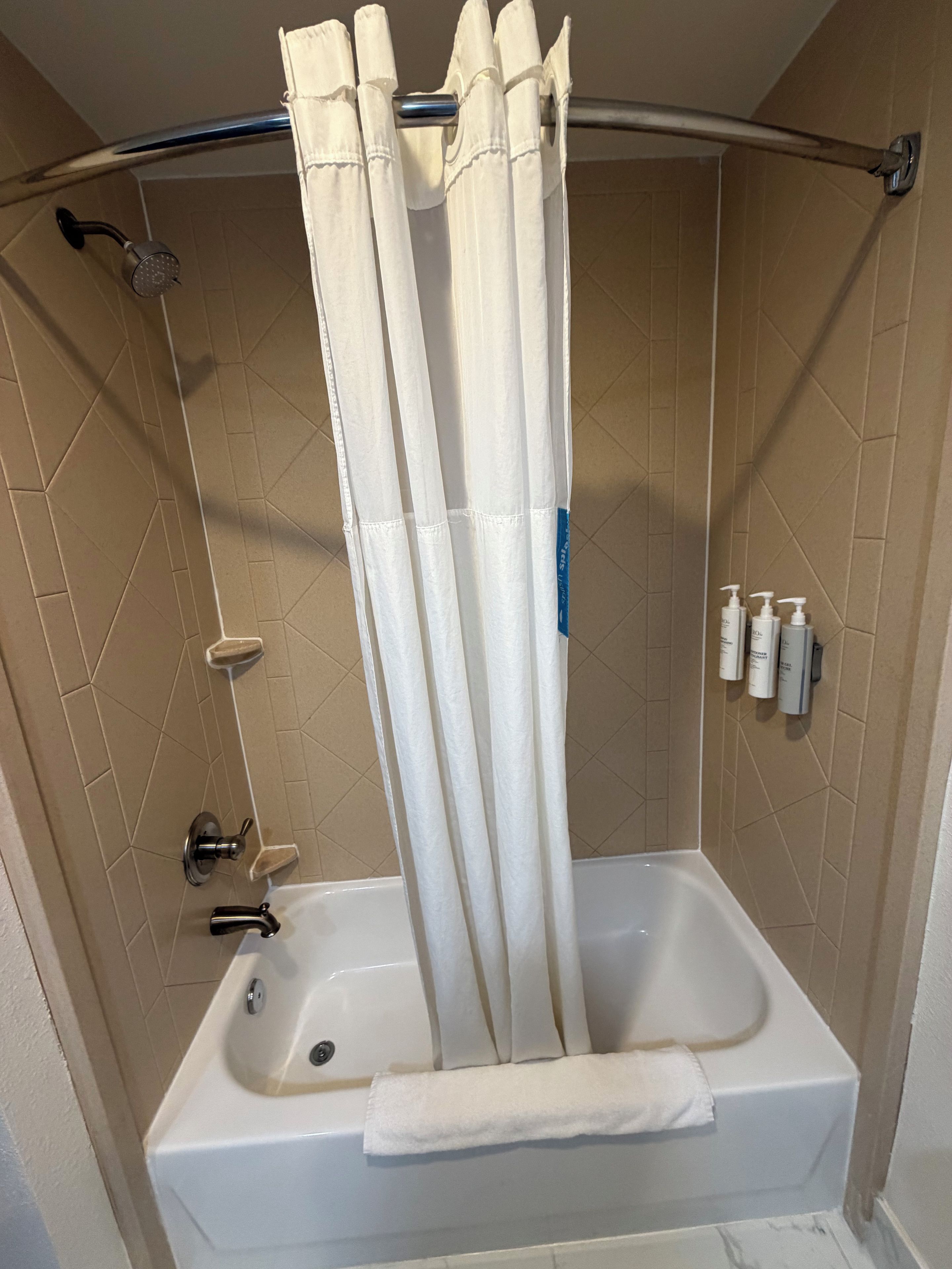 Un bagno con vasca, tenda doccia e articoli da toilette a parete.
