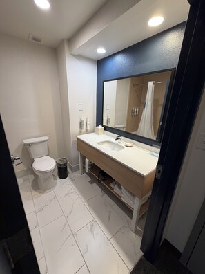 Un baño moderno con inodoro, lavamanos y espejo.
